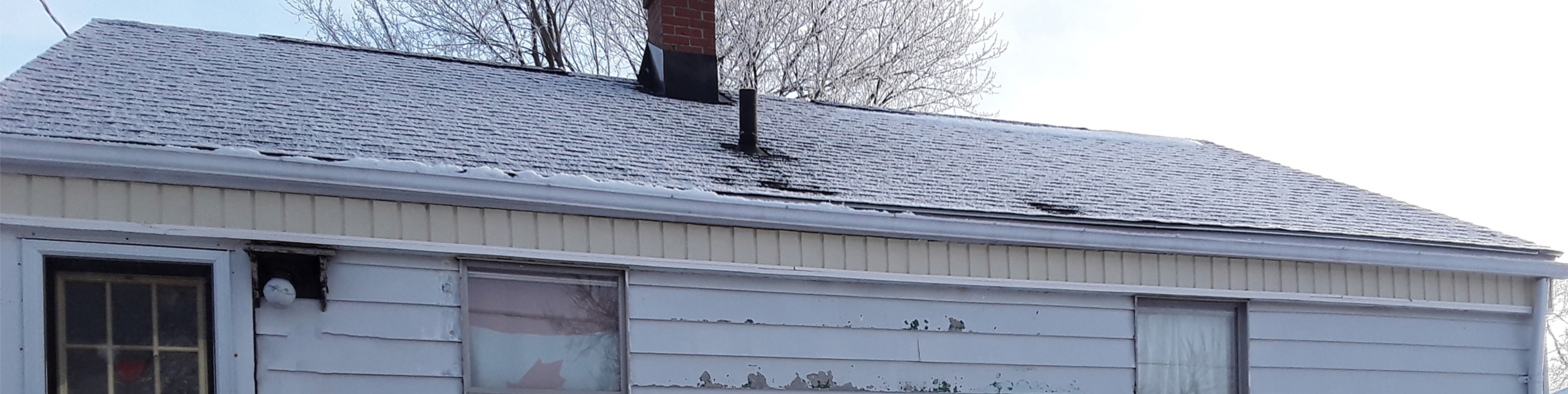 Roof of house in winter, in need of repairs.
