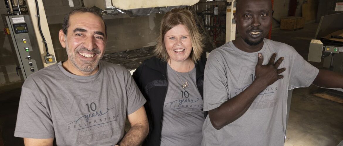 Three workers share a laugh on the factory floor.