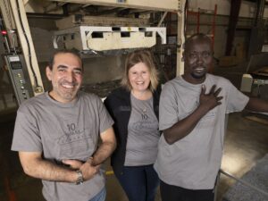 Three workers share a laugh on the factory floor.