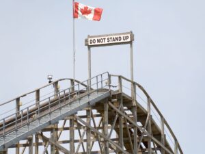 A warning sign reading “do not stand up” at the top of a wooden rollercoaster.